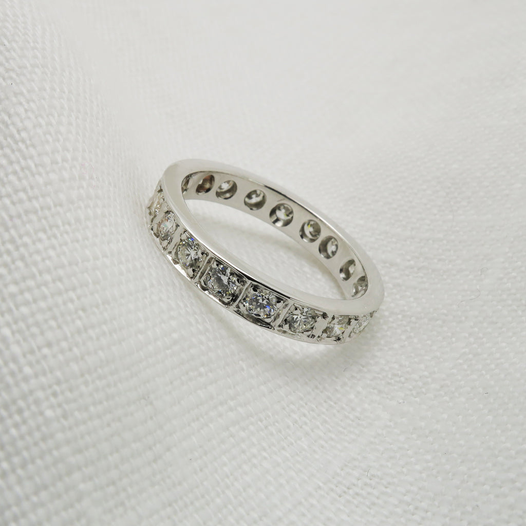 18ct white gold diamond set wedding band rests on an angle on white fabric.